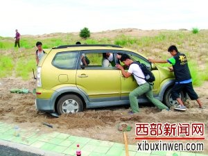 在运送火箭过程中，汽车陷在沙里，航天爱好者们一起用手推车。